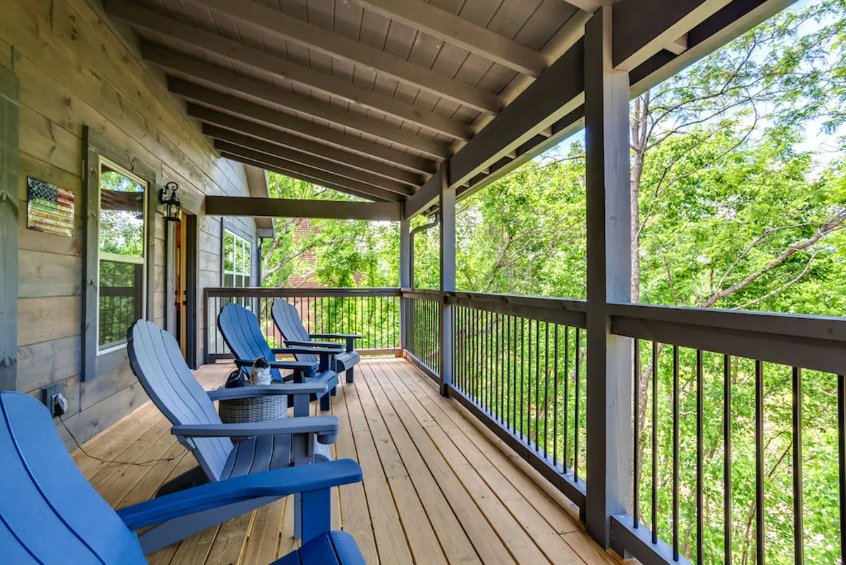A cozy balcony scene featuring blue Adirondack chairs arranged to face out toward lush trees and distant mountains. The setup is perfect for sipping morning coffee, quiet reading, or enjoying sunrise and sunset views. The atmosphere is serene and inviting.