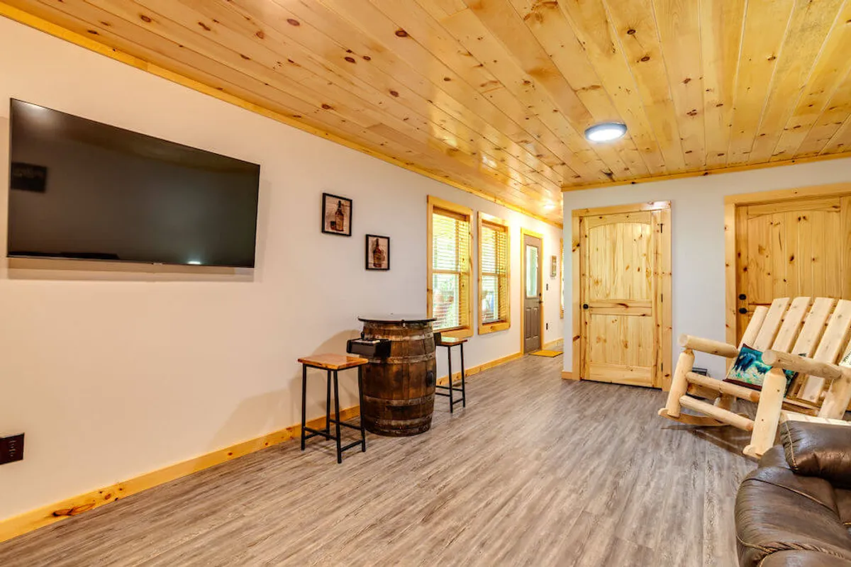 This cozy interior features a television, barrel table, wooden rocking chair, and framed pictures, offering ample space for both play and relaxation. The arrangement suggests an area perfect for watching TV, playing games, or sharing stories.
