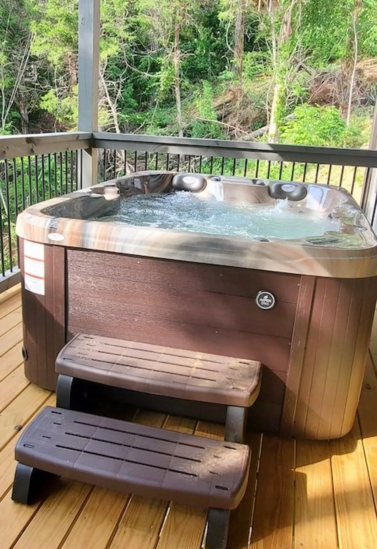 A tranquil outdoor space with a private hot tub surrounded by wooden steps and lush greenery. The setting is peaceful and inviting, ideal for relaxing after a day of adventure.