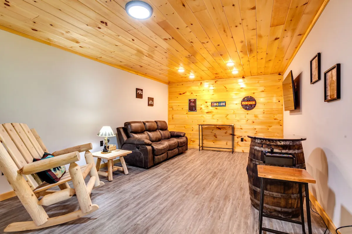 This image features a reclining sofa and a rocking chair arranged around a wooden barrel table, with a wall-mounted TV as a focal point. The warm wooden interior and inviting lighting create a welcoming atmosphere ideal for group relaxation, conversation, and entertainment.